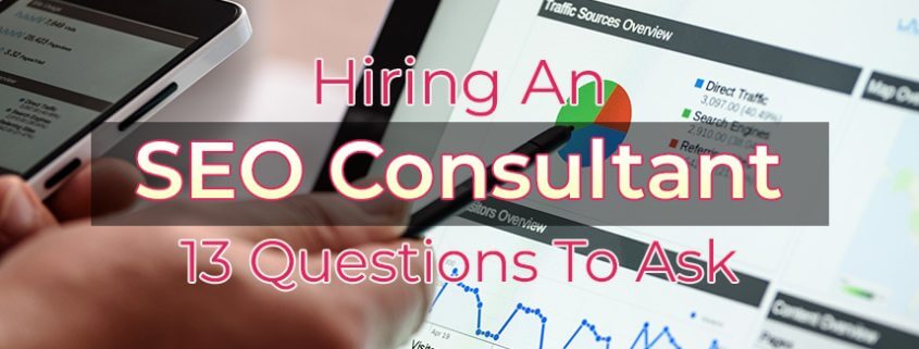 An image of the blog title "Hiring an SEO Consultant 13 Questions to Ask" with a background of a close up of a hand holding a mobile phone and a pen pointing to a tablet screen